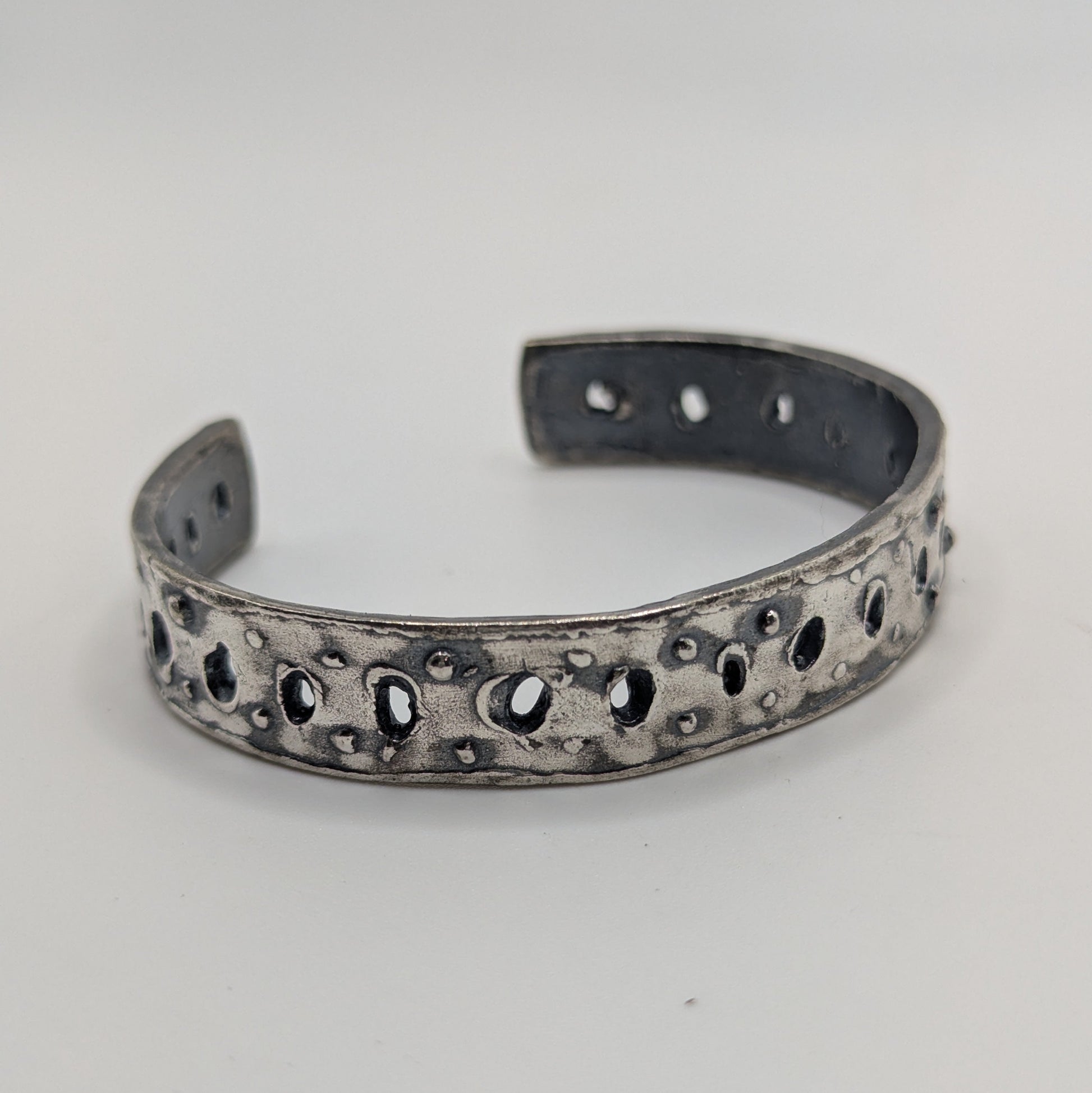 Silver bracelet with intricate design on a white background