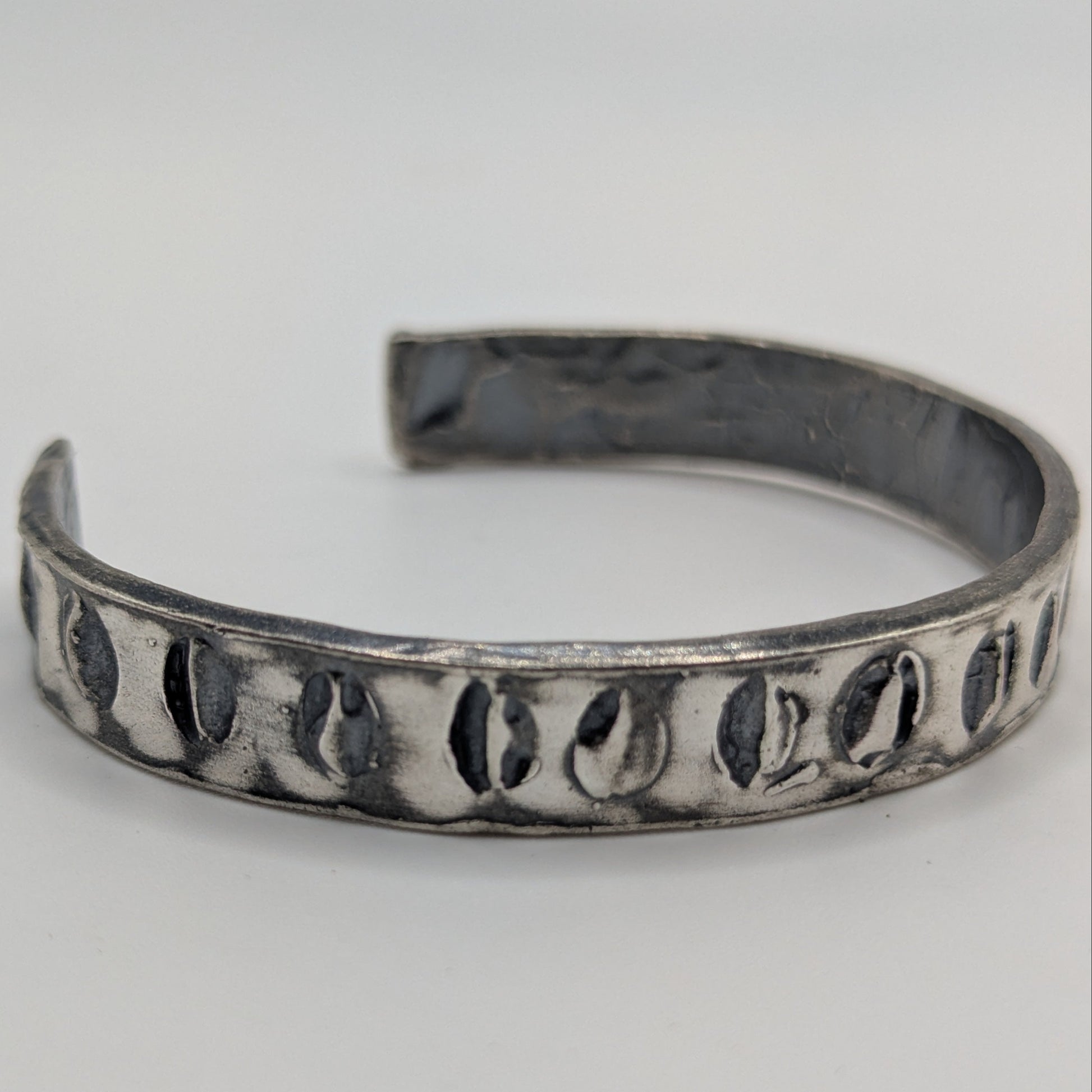 Silver bracelet with textured pattern on a light gray background