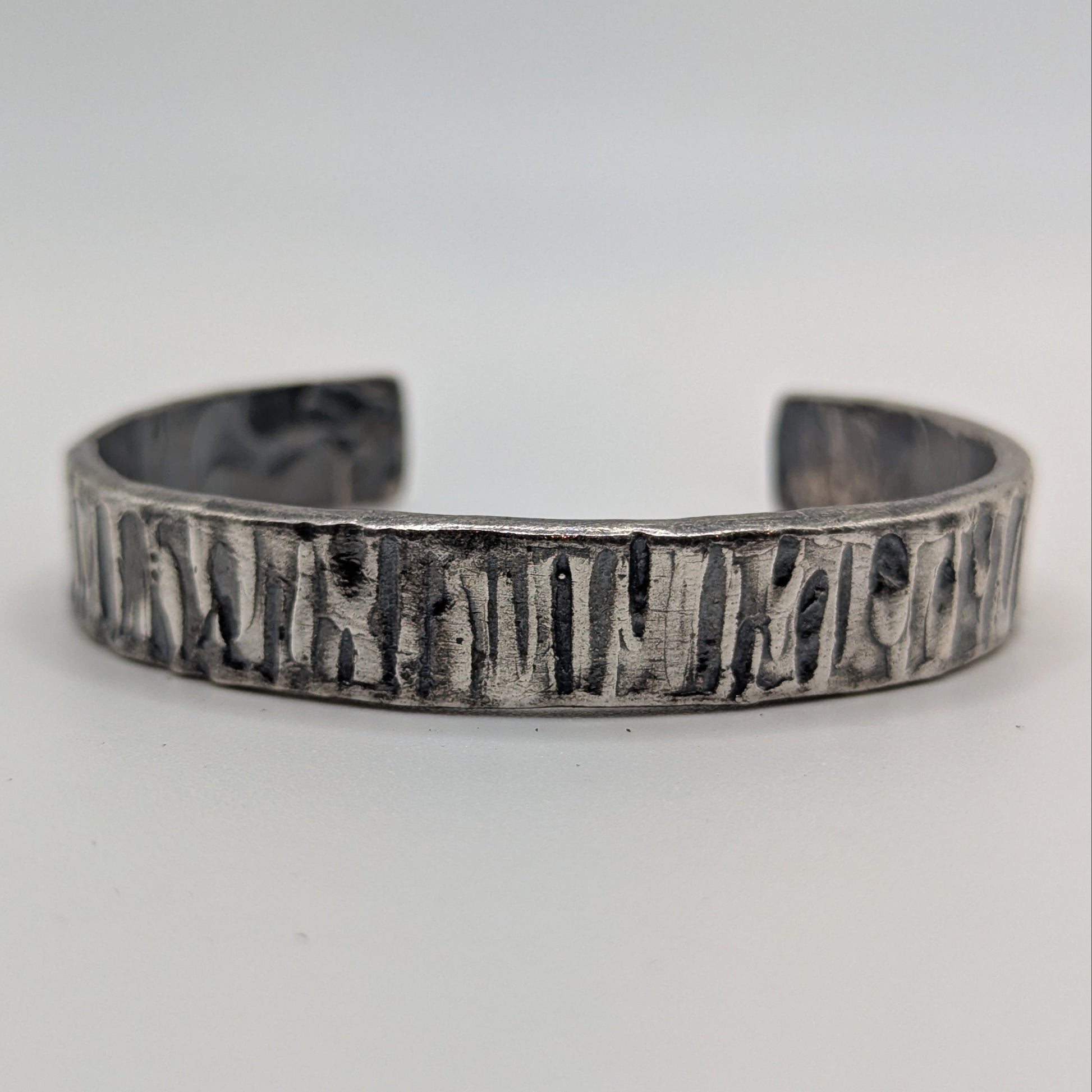 Silver bracelet with text on a light gray background