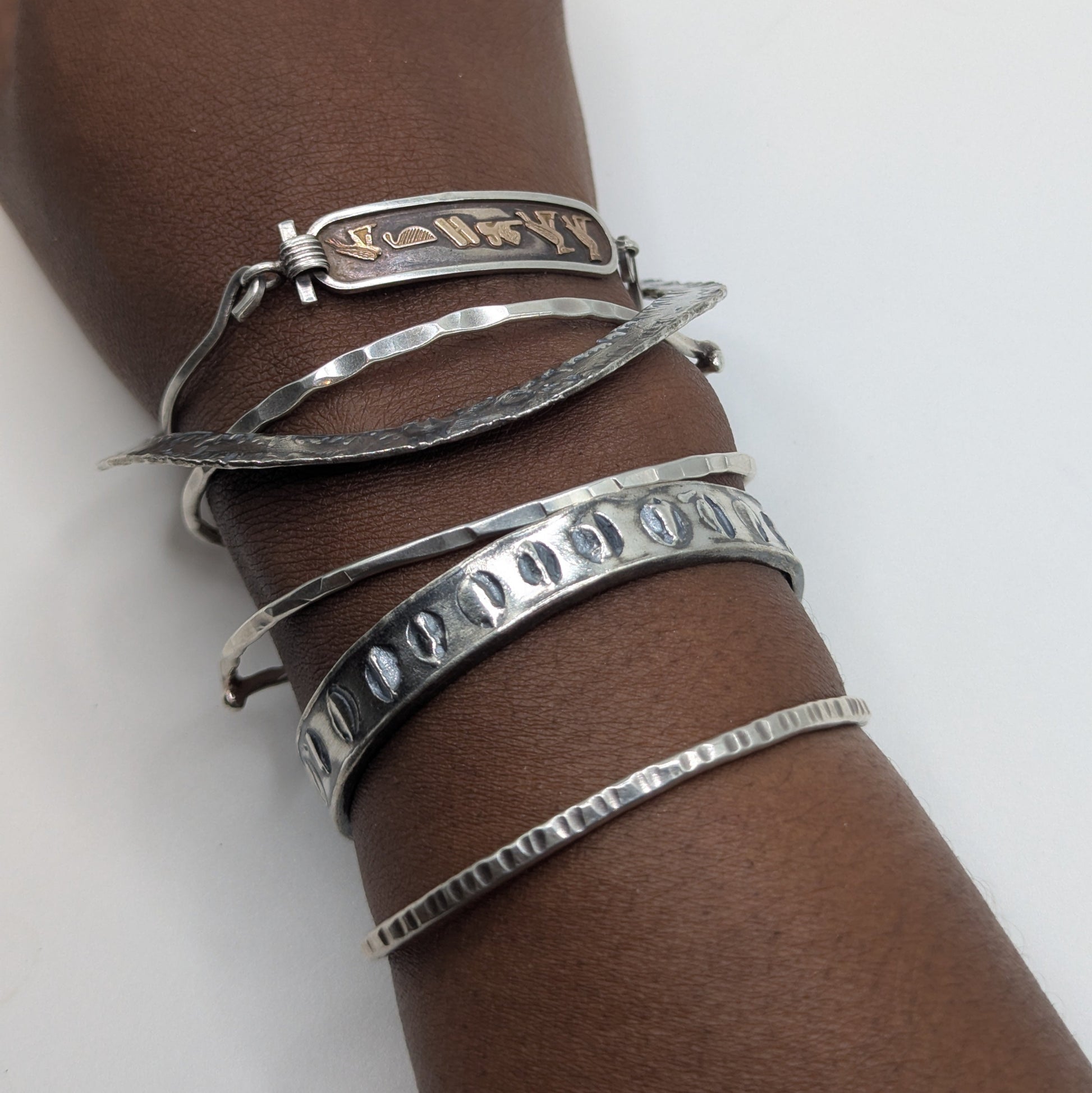 Silver bracelets on a wrist against a white background