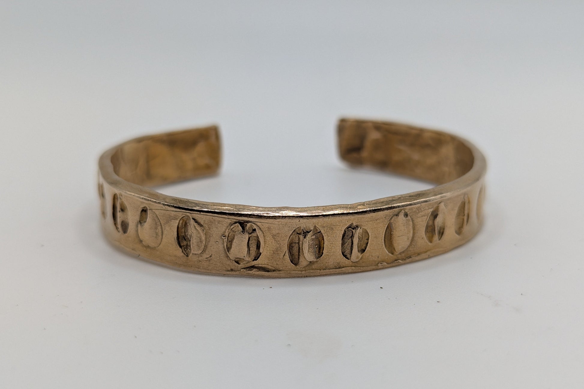 Bronze bracelet with engraved pattern on a white background