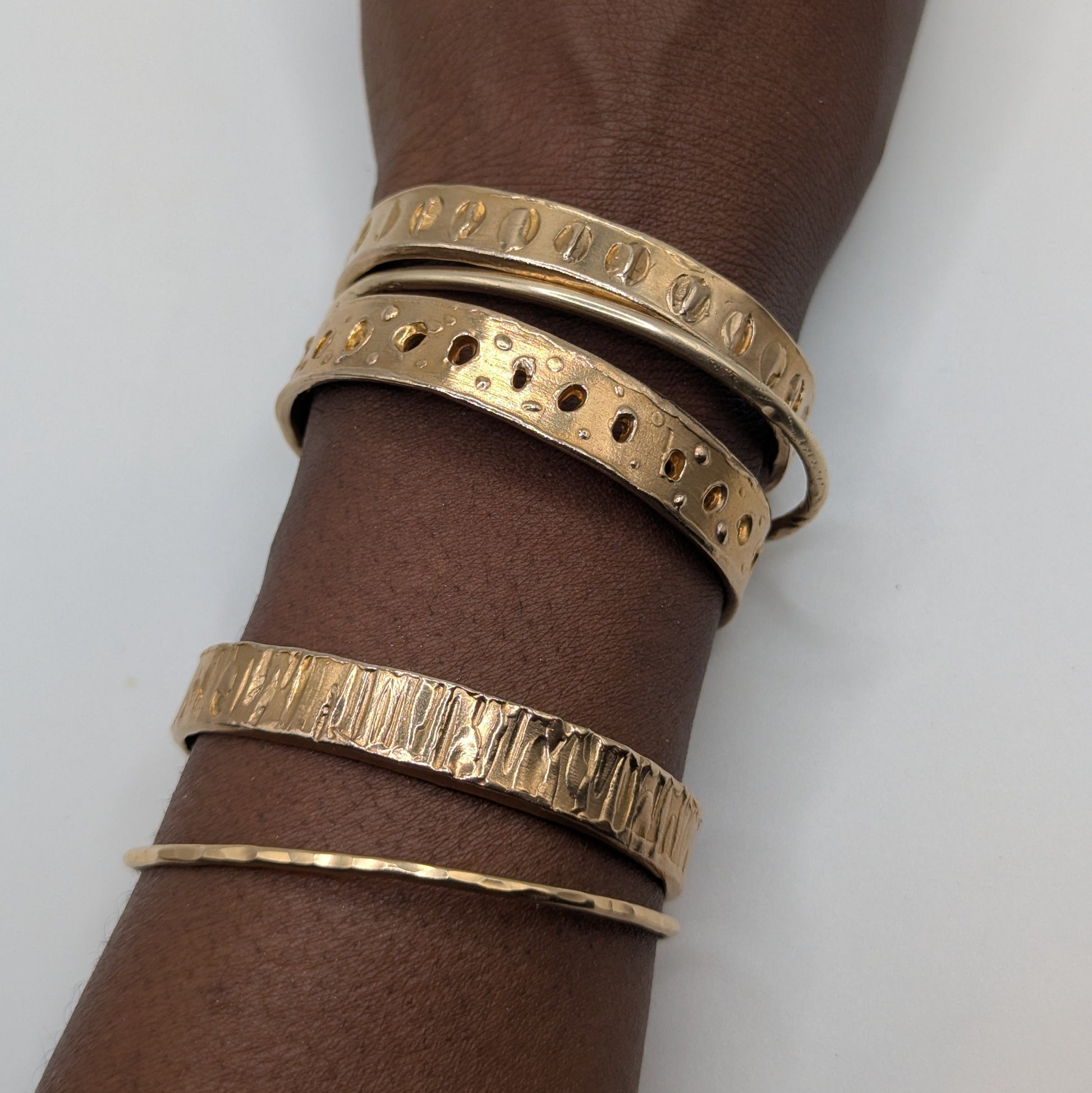 Gold bracelets on a wrist against a white background