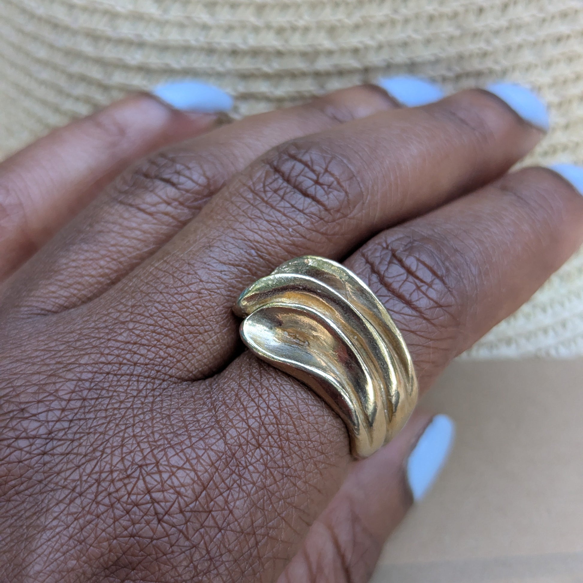 Gold ring on a person's finger with a neutral background