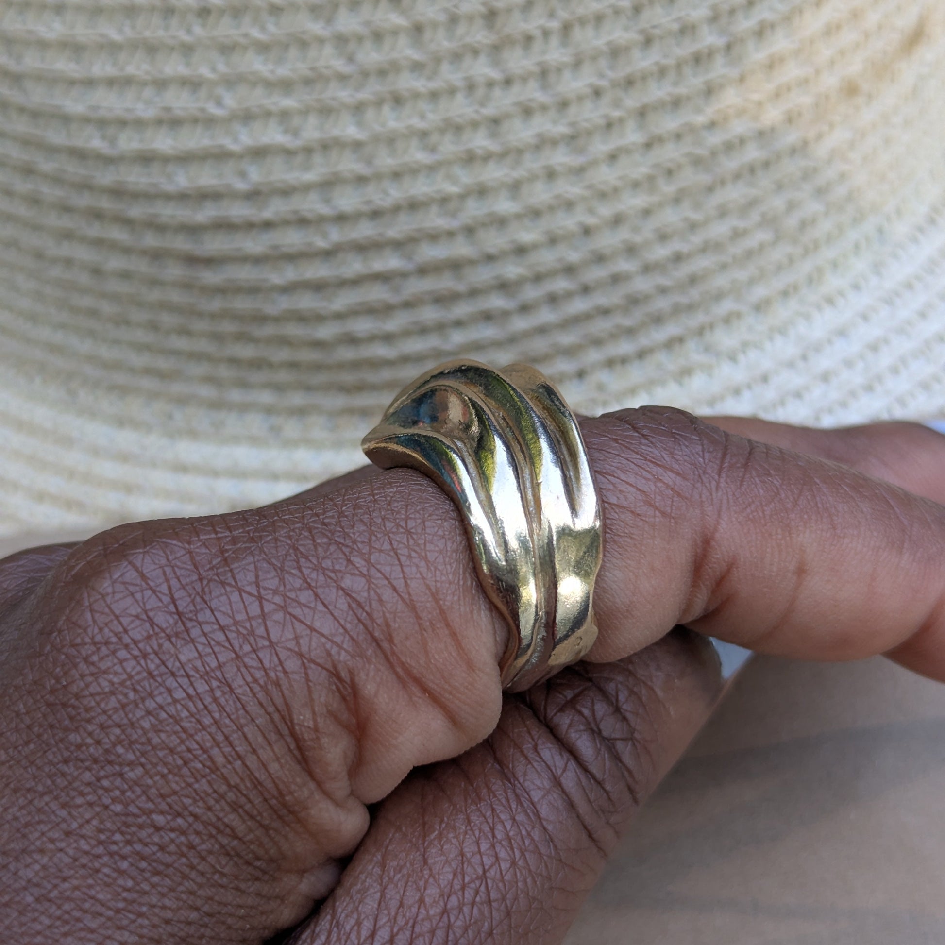 Gold ring on a finger against a neutral background